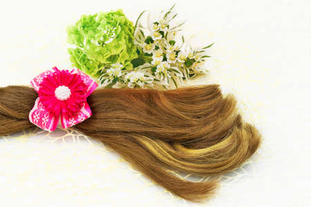 Hair and barrette with pink ribbon, white flowers and green leaf on white lace background.の写真素材