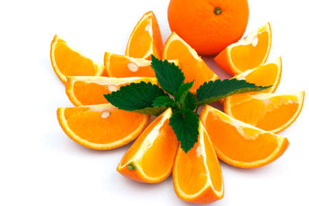 Macro view of orange with sections and fresh green leaf of mint on white backgroundの写真素材