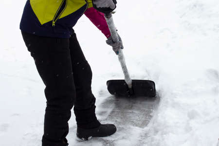 A person cleans snow with a shovel, cleans paths after a snowfall in winter. Snowy day, cleaning of the territory.の写真素材