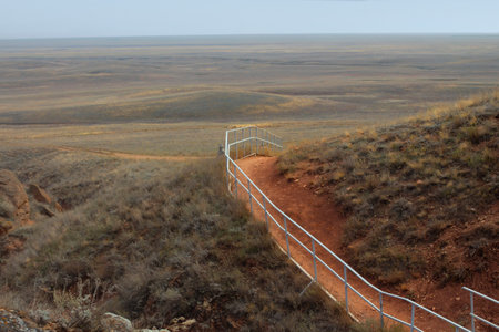 Beautiful mountainous terrain. Steppe landscape with stairs leading to the mountains, dry grass. View from a height, panorama. Horizontal orientation. Background for posters, calendarsの写真素材