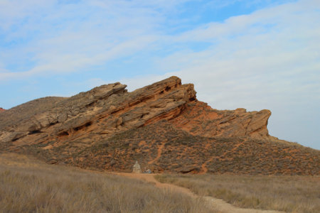 Beautiful mountainous terrain. Steppe panoramic landscape with a rocky mountain, dry grass and a road going to the statue of a Buddhist sage monk. Panoramic view. Background for posters, calendarsの写真素材