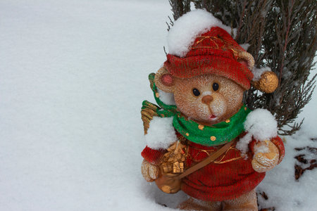 Souvenir garden figurine. A Christmas bear in a hat and scarf on the background of a winter landscape. A magical holiday scene with a place for the text. Perfect for Christmas and winter designsの写真素材