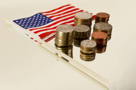 Different American coins in the column and the American flag on the reflecting surface.の写真素材