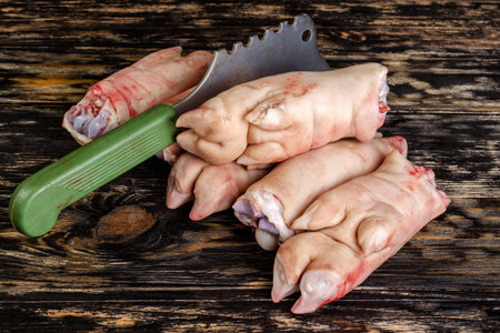 Raw and freesh pork feet or legs,over dark wooden board. They are stacked pile. With a cutting ax. Food meat shot. Close-up.の写真素材