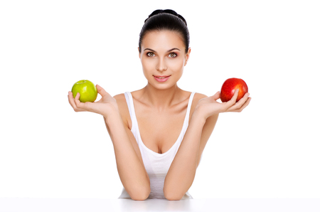 portrait of attractive caucasian smiling woman isolated on white studio shot looking at camera. It keeps  red and green apples.の写真素材