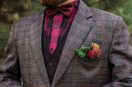 Cool Boutonniere on hip trendy groom at wedding. Grey suit, colorful vinous boutonniere. Maroon Bow tie.の写真素材