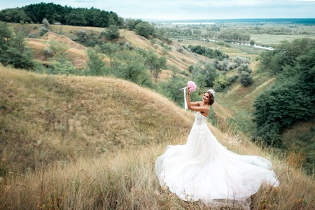 Portrait of a young beautiful bride on a background of a gorgeous view. Girl in wedding dressの写真素材