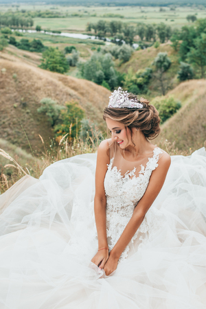 Portrait of a young beautiful bride on a background of a gorgeous view of the river and fields.の写真素材