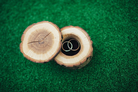 Wedding rings in a beautiful and stylish wooden box, on a green background. The concept of a wedding, the ceremony of betrothal. Gold rings newlyweds.の写真素材