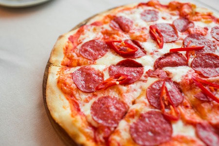 Spicy pizza with cheese and pepperoni. Pepperoni pizza with sausages on table.の写真素材