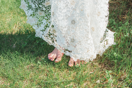 Young girl, the bride stands barefoot on the grass. Parts of the body, legs without shoes.の写真素材