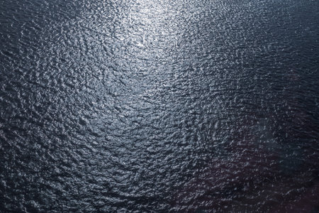 The texture of dark blue water of a river or lake with small waves and ripples on the surface of the...