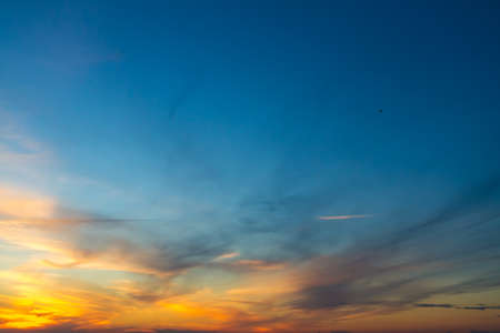 The sky at sunset or sunrise with orange clouds and a blue tint.の写真素材