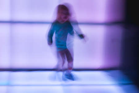 Children dance at the disco on glowing panels, blurry background. Blurry movement of people dancing.の写真素材