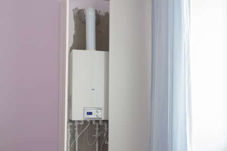 A double-circuit boiler for heating in a residential building is hidden in a white cabinet to be invisible in the interior.の写真素材