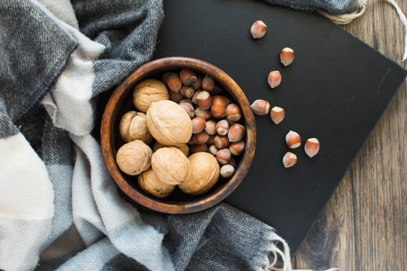 Wooden cup with assorted nuts on a black background on a wooden table.の写真素材