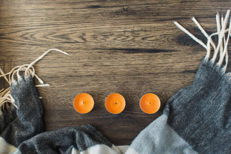 Autumn composition. Frame made of knitted blanket or scarf, scented candles. Autumn, fall concept. Flat lay, top view, copy space.の写真素材