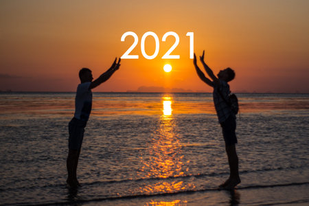 Two men holding the New Year 2021 against the background of the sun.