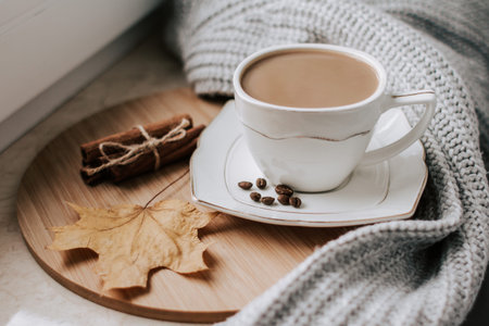 cup of coffee with coffee beans and cinnamon sticks.