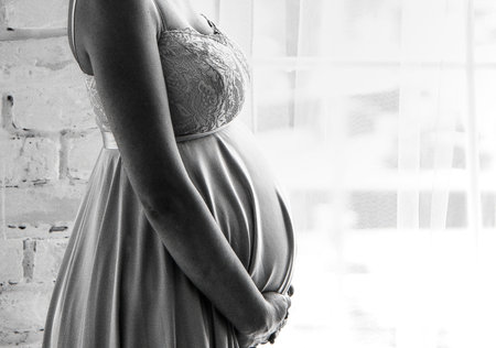pregnant woman with a big belly at the window. Black and white photographyの写真素材