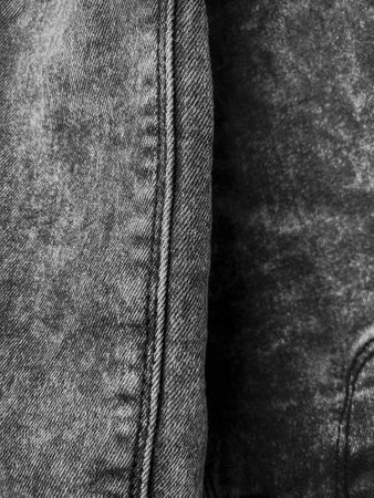 Gray jeans texture, vertical photo, decorative for background. Popular clothes, design element, seam, shades of gray color. Tissue product, beauty and fashionの写真素材