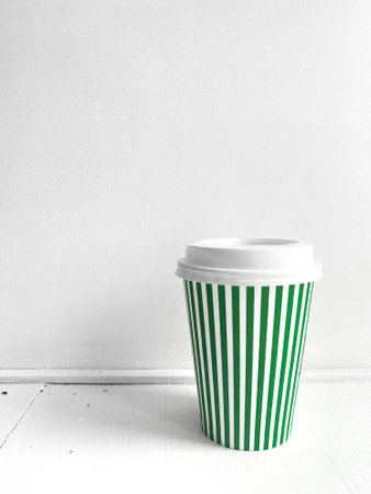 Green striped coffee cup, vertical photo. Street food coffee to go, closed plastic cup for various drinks and beverages on white background. Single object, take awayの写真素材