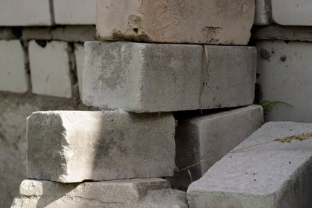 Stack of white concrete brick blocks, horizontal photo. Construction industry, building material. Outdoor, dry herbs, blurred backgroundの写真素材