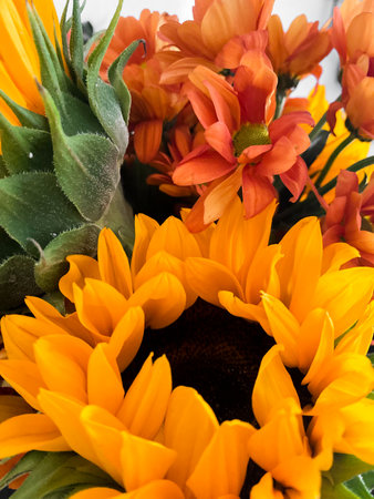 Beautiful floral bouquet with vibrant sunflowers mixed with orange and yellow flowers. Sunflowers with bold petals, smaller blooms add pop of color. Lively display perfect for decor or celebrationsの写真素材