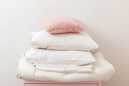 A pile of clean ironed bedding and a towel lies on the dresser.の写真素材