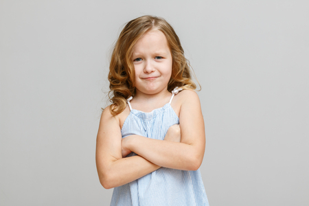 Portrait of a little girl on a gray background. Child is angryの写真素材