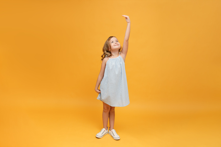 A little child measures her height on a yellow background. Concept of development, goal, successの写真素材