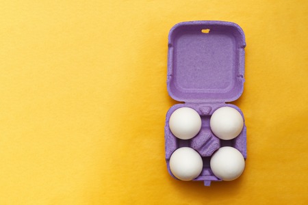 Easter composition. Set of Four white eggs in purple box on  yellow backgroundの写真素材