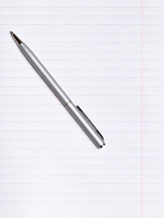 On a sheet of paper notebook with lines lies a silver pen. Copy space. Education conceptの写真素材