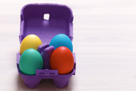 Easter composition. A set of four colorful eggs in a purple box on a white table. Copy spaceの写真素材