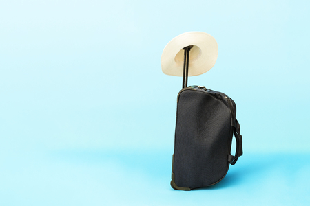 Suitcase and hat on a blue background. The concept of travel and vacation.の写真素材