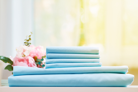 Closeup stack of blue clean bedding on the table. Blurred background.の写真素材
