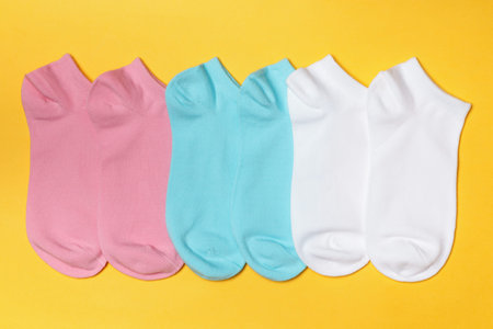 Set of short socks in white, pink, blue on a yellow background.