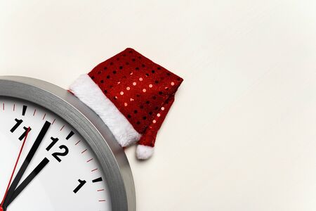 Clock with a Christmas cap on a white background.の写真素材