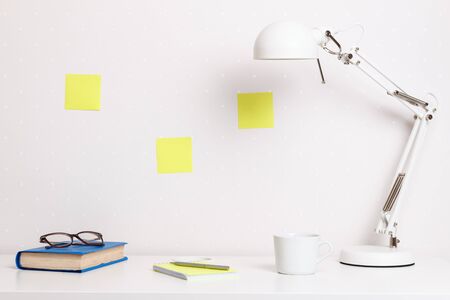 Work desktop at home and office with white lamp glasses book office supplies. The concept of modern space.の写真素材
