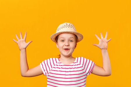 Cheerful happy cute little girl in a straw hat laughs and shows palms. Closeup portrait of a child...