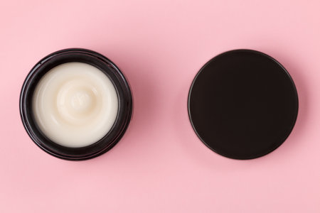 Cosmetic face cream in an open jar on a pink background.の写真素材