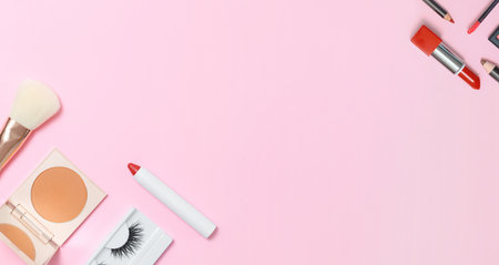 Decorative cosmetics on a pink background. Compact Powdery Makeup Brush False Eyelashes Lipstick Pencils. Banner copy space flat lay top view.の写真素材