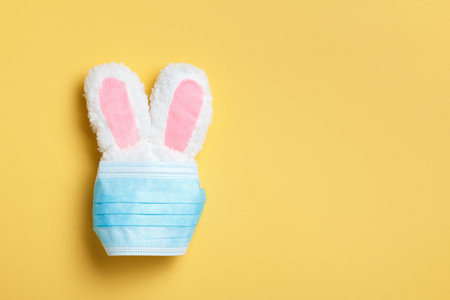 Quarantine easter concept. Rabbit in a protective medical mask on a yellow background.の写真素材