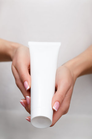 A young girl holds a tube with a cosmetic product in her hands. Skin care concept, youthfulness and...