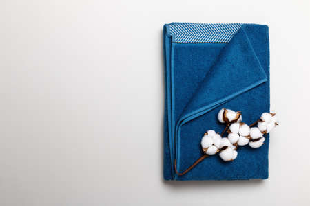 Top view of folded blue towel with cotton branch on gray background.の写真素材