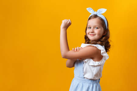 Portrait of a preteen on a yellow background. Girl power concept.の写真素材
