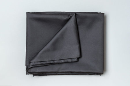 Close-up top view of a set of dark bed sheets and duvet cover on a gray background.の写真素材