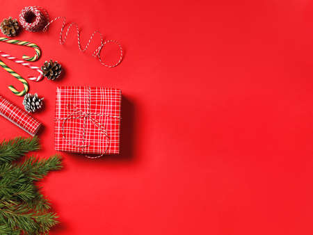 New Year's composition. Christmas gift, pine cones, fir branches on a red background. Flat lay, top view, copy spaceの写真素材