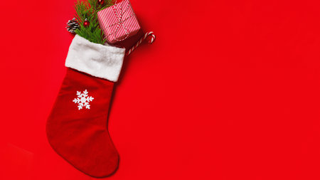 Christmas stocking with a gift on a red background with copy space.