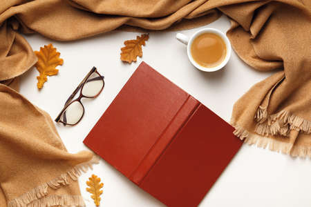 Autumn composition. Open inverted book glasses cashmere scarf, coffee cup with autumn leaves on a white background. Flat lay top viewの写真素材